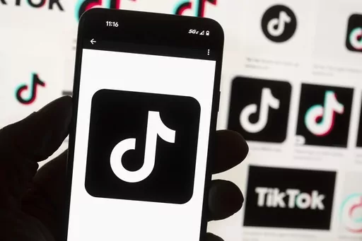 The TikTok logo is seen on a mobile phone in front of a computer screen which displays the TikTok home screen, Oct. 14, 2022, in Boston. Lawmakers in Georgia, early Friday, March 29, 2024, approved a bill that would require parental permission before children younger than 16 could sign up for social media accounts. (AP Photo/Michael Dwyer, File)