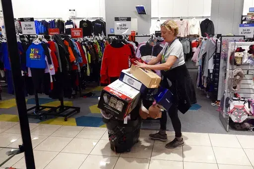 FILE - A shopper pushes her cart full of items down an isle during a Black Friday sale at Macy's, Friday, Nov. 26, 2021, in Indianapolis.  Holiday sales rose at the fastest pace in 17 years, even as shoppers grappled with higher prices, product shortages and a raging new COVID-19 variant in the last few weeks of the season,  according to one spending measure. (AP Photo/Darron Cummings, File)
