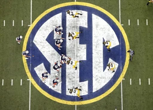 Auburn quarterback Nick Marshall (14), left, takes the snap from Auburn center Reese Dismukes (50) as the Auburn offense operates against Missouri on the SEC logo during the first half of Auburn's 59-42 win over Missouri in the SEC Championship at the Georgia Dome, Saturday, Dec. 7, 2013, in Atlanta, Ga. Southeastern Conference and Pac-12 officials are expected to provide the final approval of a $2.8 billion plan that will settle antitrust claims and set the stage for college athletes to start s
