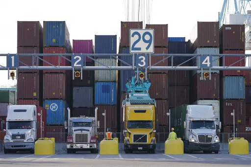 Trucks line up to have containers loaded from a stack at the Norfolk International Terminal Wednesday Dec 1, 2021, in Norfolk, Va.  Walmart workers who once unloaded trucks now have a chance to drive them. The nation’s largest retailer has launched a training program for employees who work in its distribution or fulfillment centers.   (AP Photo/Steve Helber, File)