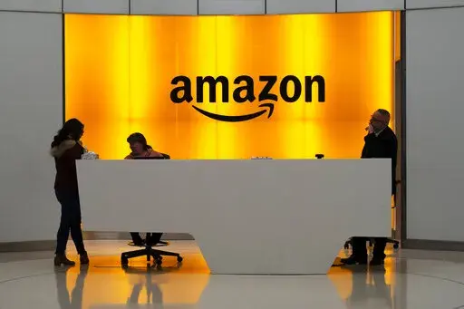 In this Feb. 14, 2019 file photo, people stand in the lobby for Amazon offices in New York. Amazon is ending a charity donation program it ran for a decade in its latest cost-cutting move. In a blog post on Wednesday, Jan. 18, 2023, the company said the program, called AmazonSmile, will shut down by February 20. (AP Photo/Mark Lennihan, File)