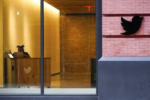 A receptionist works in the lobby of the building that houses the Twitter office in New York, Wednesday, Oct. 26, 2022. Elon Musk has emailed Twitter employees ordering them to return to the office starting Thursday for at least 40 hours a week and warning of “difficult times ahead.”  (AP Photo/Mary Altaffer)