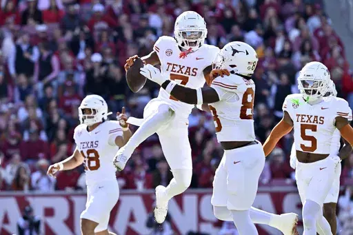 Texas defensive back Jahdae Barron (7) celebrates with teammate Barryn Sorrell (88) after making in interception against Arkansas during the first half of an NCAA college football game Saturday, Nov. 16, 2024, in Fayetteville, Ark. (AP Photo/Michael Woods)