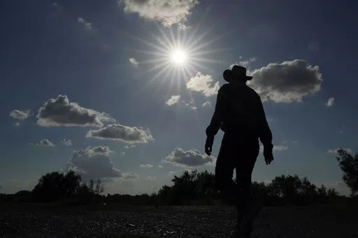 Jessie Fuentes, who works providing people with canoes and kayaks, walks along the Rio Grande with the sun pushing the temperature into the 90s on July 6, 2023. The death certificates of more than 2,300 people who died in the United States last summer mention the effects of excessive heat, the highest number in 45 years of records, according to an Associated Press analysis of Centers for Disease Control and Prevention data. With May already breaking heat records, 2024 could be even deadlier. (AP
