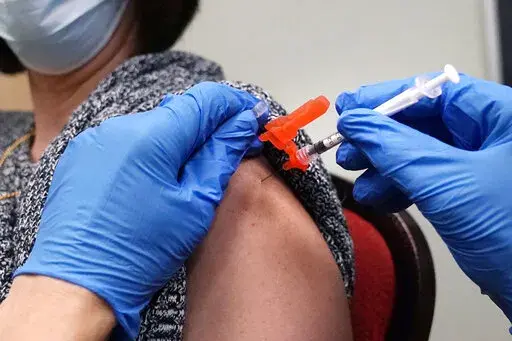 A woman receives a COVID-19 vaccine injection by a pharmacist at a clinic in Lawrence, Mass., on Wednesday, Dec. 29, 2021.   On Friday, March 11, 2022, The Associated Press reported on stories circulating online incorrectly claiming people who have received COVID-19 vaccine booster shots are at a greater risk of dying from the virus.  (AP Photo/Charles Krupa, File)