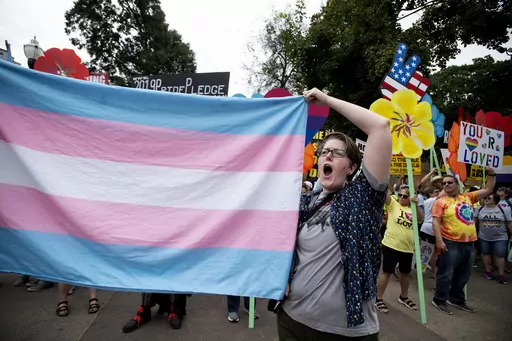A supporter for the transgender community holds up a flag in front of counter-protesters at the city's Gay Pride Festival, Oct. 12, 2019, in Atlanta. Courts nationwide are delivering a mixed verdict on the future of state laws restricting gender-affirming medical care for transgender youth, as legal battles ramp up over the historic wave of bans enacted in 2023. (AP Photo/Robin Rayne, File)