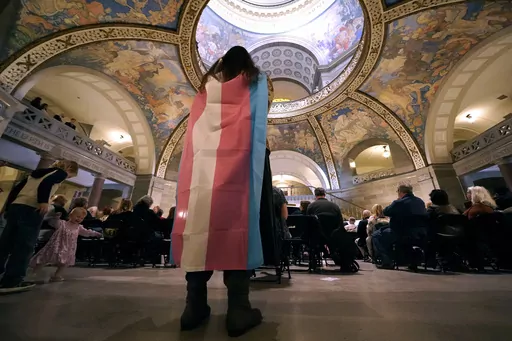 Glenda Starke wears a transgender flag as a counter protest during a rally in favor of a ban on gender-affirming health care legislation, March 20, 2023, at the Missouri Statehouse in Jefferson City, Mo. A judge's ruling striking down Arkansas' first-in-the-nation ban on gender-affirming care for minors, on June 20, is offering hope to transgender people, families and providers after a historic wave of restrictions on trans people's lives sailed through Republican statehouses this year. (AP Phot
