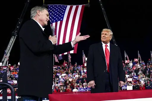 Former Sen. David Perdue of Georgia, speaks as President Donald Trump looks on, at a campaign rally at Valdosta Regional Airport, Dec. 5, 2020, in Valdosta, Ga. Perdue is building his campaign around Donald Trump and veering to the right as he tries to unseat Republican Gov. Brian Kemp in a May 24 GOP primary. (AP Photo/Evan Vucci, File)