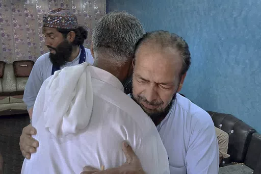 People offer their support to Raja Yousaf, right, whose son Raja Sajid is missing after a shipwreck off the Greek coast, in Bindian village in Kotli, a district of Pakistan's administrator Kashmir, Sunday, June 18, 2023. Pakistani Prime Minister Shehbaz Sharif declared a national day of mourning for citizens who died when the fishing trawler packed with migrants they were in sank off the Greek coast. (AP Photo/Nasir Mehmood)