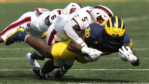 Michigan running back Kalel Mullings (20) is brought down by Arkansas State safety Dontay Joyner (6) and Marvin Ham (5) in the first half of an NCAA college football game in Ann Arbor, Mich., Saturday, Sept. 14, 2024. (AP Photo/Paul Sancya)