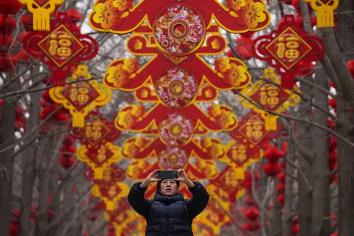 A woman takes a picture of red lanterns and decorations on display along the trees ahead of the Chinese Lunar New Year at Ditan Park in Beijing, Feb. 4, 2024. In many Asian cultures, the Lunar New Year is a celebration marking the arrival of spring and the start of a new year on the lunisolar calendar. It's the most important holiday in China where it's observed as the Spring Festival. (AP Photo/Andy Wong, file)