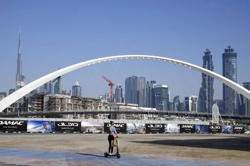 A woman rides a scooter while passing by the advertising billboards of a new residential project in Dubai, United Arab Emirates, Tuesday, Jan. 31, 2023. For the first time since a 2009 financial crisis nearly brought Dubai to its knees, several major abandoned real estate projects now show signs of life. As with its other booms, war again is driving money into Dubai and buoying its economy. This time it's Russian investors fleeing Moscow’s war on Ukraine, rather than people escaping Mideast ba