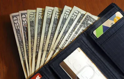 In this June 15, 2018, file photo, cash is fanned out from a wallet in North Andover, Mass. You share a lot with your spouse, but your credit score isn’t one of those things. Even if you don’t earn an income and your spouse supports you financially, it’s important to build your own credit score. Not only will your score come into play when you apply for a joint loan, but you may need to fall back on it if you ever become single again. You can build credit by using your spouse’s income on
