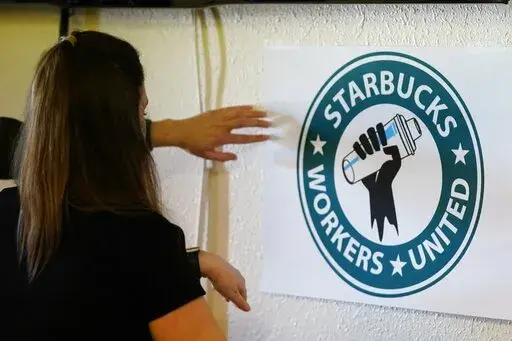 Michelle Eisen, a barista at the Buffalo, N.Y., Elmwood Starbucks location, helps out the local Starbucks Workers United, employees of a local Starbucks, as they gather at a local union hall to cast votes to unionize or not, on Feb. 16, 2022, in Mesa, Ariz. Federal labor officials filed a sweeping complaint Friday, May 6, 2022 accusing Starbucks of unfair labor practices at its stores in Buffalo, New York, including retaliation against pro-union employees.(AP Photo/Ross D. Franklin, File)