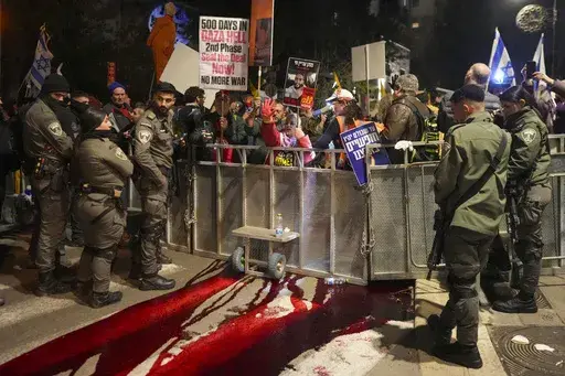 Relatives and supporters of Israelis held hostage by Hamas in Gaza spill a red liquid, symbolizing blood, in Jerusalem, Israel, Monday, Feb. 17, 2025, during a rally marking 500 days of captivity and demanding their release. (AP Photo/Ohad Zwigenberg)