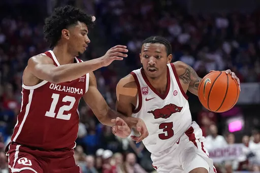 Arkansas guard Nick Smith Jr. (3) drives around Oklahoma guard Milos Uzan (12) in the second half of an NCAA college basketball game Saturday, Dec. 10, 2022, in Tulsa, Okla. (AP Photo/Sue Ogrocki)