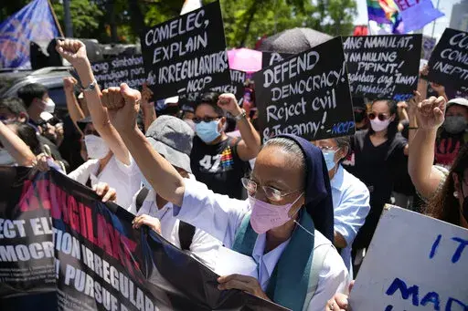 A Catholic nun clenches her fist as she joins protesters against presidential frontrunner Ferdinand "Bongbong" Marcos and running mate Sara Duterte, daughter of the current president, during a rally in Pasay, Philippines, Friday, May 13, 2022. Allies of the Philippines' presumptive next president, Marcos Jr., appear set to strongly dominate both chambers of Congress, further alarming activists after the late dictator's son scored an apparent election victory that will restore his family to the s