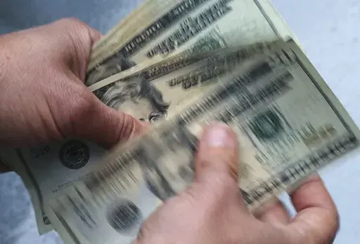 Twenty dollar bills are counted in North Andover, Mass., on June 15, 2018. Money is getting tighter for many folks — and probably for you. Yet there may be charitable organizations you want to support, friends or family asking for financial help and things you want to buy for yourself. It’s possible to do these things even on a limited budget. (AP Photo/Elise Amendola, File)