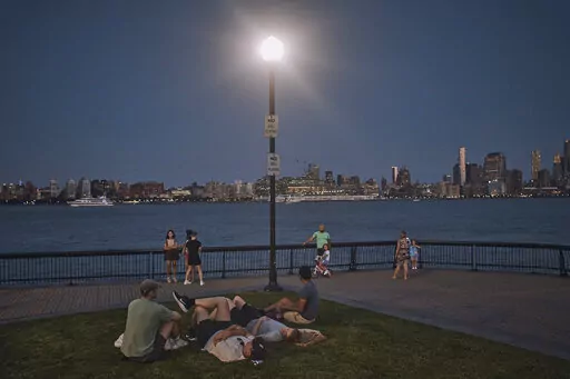 People spend time at the park at dusk during a summer heat wave, July 21, 2022, in Hoboken, N.J. The continental United States in July set a record for overnight warmth, providing little relief from the day’s sizzling heat for people, animals, plants and the electric grid, meteorologists said. (AP Photo/Andres Kudacki, File)