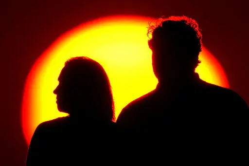 A couple watches the sun set from a park Saturday, July 10, 2021, in Kansas City, Mo. Debts brought into a relationship can be ruinous for couples, but many decide to work as a team to conquer individual debts. (AP Photo/Charlie Riedel, File)