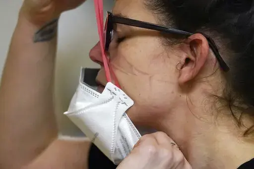 Registered nurse Jessalynn Dest pulls on a new N95 mask as indentations remain from another she had just removed after leaving a COVID-19 patient room in the acute care unit of Harborview Medical Center, Jan. 14, 2022, in Seattle. The Biden administration will begin making 400 million N95 masks available for free to Americans starting next week, now that federal officials are emphasizing their better protection against the omicron variant of COVID-19 over cloth face coverings.  The White House a
