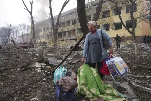 A woman walks outside the damaged by shelling maternity hospital in Mariupol, Ukraine, Wednesday, March 9, 2022. A Russian attack has severely damaged a maternity hospital in the besieged port city of Mariupol, Ukrainian officials say. (AP Photo/Evgeniy Maloletka)