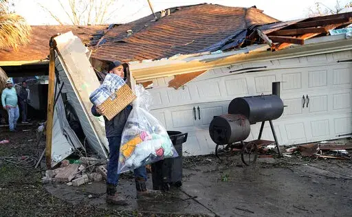 Mario Mendoza carries items out of a friend's storm-damaged home Tuesday, Jan. 24, 2023, in Pasadena, Texas. A powerful storm system took aim at Gulf Coast Tuesday, spawning tornados that caused damage east of Houston. (AP Photo/David J. Phillip)