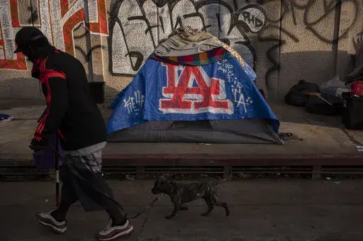 A man walks past a homeless encampment in downtown Los Angeles, Wednesday, Oct. 25, 2023. (AP Photo/Jae C. Hong, File)