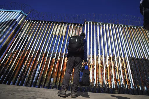 A migrant waits of the Mexican side of the border after United States Customs and Border Protection officers detained a couple of migrants crossing the US-Mexico border on the beach, in Tijuana, Mexico, Jan. 26, 2022. About 3 in 10 also worry that more immigration can cause native-born Americans to lose their economic, political and cultural influence, according to a poll by The Associated Press-NORC Center for Public Affairs Research. (AP Photo/Marco Ugarte, File)