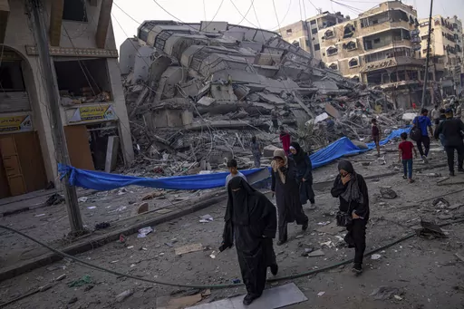 Palestinians walk by the rubble of a building after it was struck by an Israeli airstrike, in Gaza City, Sunday, Oct. 8, 2023. The militant Hamas rulers of the Gaza Strip carried out an unprecedented, multi-front attack on Israel at daybreak Saturday, firing thousands of rockets as dozens of Hamas fighters infiltrated the heavily fortified border in several locations by air, land, and sea, killing hundreds and taking captives. Palestinian health officials reported scores of deaths from Israeli a