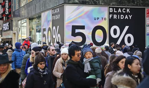 Crowds walk past a large store sign displaying a Black Friday discount in midtown Manhattan, Friday, Nov. 23, 2018, in New York. While Black Friday may no longer look like the crowd-filled, in-person mayhem that it was just decades ago — in large part due to the rising dependence on online shopping that was accelerated by the COVID-19 pandemic — the holiday sales event is still slated to attract millions of consumers. (AP Photo/Bebeto Matthews, File)