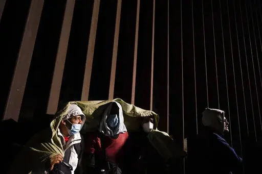 Four men from Cuba try to keep warm after crossing the border from Mexico and surrendering to authorities to apply for asylum on Nov. 3, 2022, near Yuma, Ariz. U.S. District Judge Emmet Sullivan on Tuesday, Nov. 15, ordered the Biden administration to lift Trump-era asylum restrictions that have been a cornerstone of border enforcement since the beginning of COVID-19. Sullivan ruled that Title 42 authority end immediately for families and single adults, saying it violates federal rule-making pro