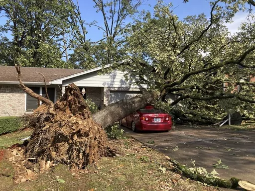 An uprooted tree damages a home and a car in a Little Rock, Ark., neighborhood on Wednesday, Sept. 6, 2023, following a severe storm. The storm hit neighborhoods that a tornado tore through last spring, damaging some of the homes rebuilding from that tornado. (AP Photo/Andrew DeMillo)