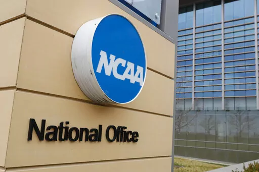 Signage at the headquarters of the NCAA is viewed in Indianapolis, March 12, 2020. By trying to limit how much schools can help college athletes cashing in on their fame, the NCAA seems to have inadvertently opened the door for boosters to get a foothold in a burgeoning market. (AP Photo/Michael Conroy, File)