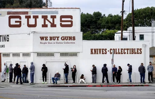In this March 15, 2020 file photo people wait in a line to enter a gun store in Culver City, Calif. The man who shot and killed four people this week at a Tulsa, Okla., hospital bought his AR-style semiautomatic rifle just hours before he began the killing spree. That would not have been possible in Washington and a half dozen other states that have waiting periods of days or even more than a week before people can take possession of such weapons. (AP Photo/Ringo H.W. Chiu, File)