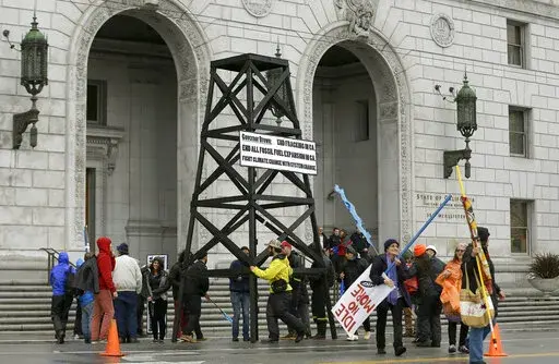 Protesters prepare to take down a makeshift oil derrick that was set up in front of the California State Office Building to protest fracking in San Francisco on Feb. 6, 2015. Leasing for new oil and gas drilling on federal land in central California is temporarily blocked under a settlement announced Monday, Aug. 1, 2022, between the state and the U.S. Bureau of Land Management. (AP Photo/Jeff Chiu, File)