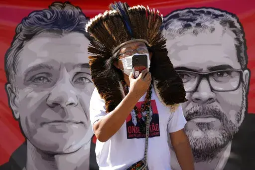 Indigenous leader Kamuu Wapichana is backdropped by a banner that show images of missing freelance British journalist Dom Phillips, left, and Indigenous expert Bruno Pereira, during a protest asking authorities to expand the search efforts for the two men, in front of the Ministry of Justice in Brasilia, Brazil, Tuesday, June 14, 2022. The search for Pereira and Phillips, who disappeared in a remote area of Brazil’s Amazon continued following the discovery of a backpack, laptop and other perso