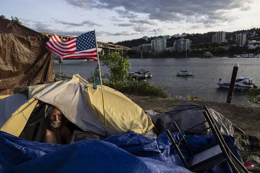 Frank, a homeless man, sits in his tent with a river view, June 5, 2021, in Portland, Ore. Momentum is building in a case regarding homeless encampments before the U.S. Supreme Court that could have major implications for cities as homelessness nationwide has reached record highs. (AP Photo/Paula Bronstein, File)
