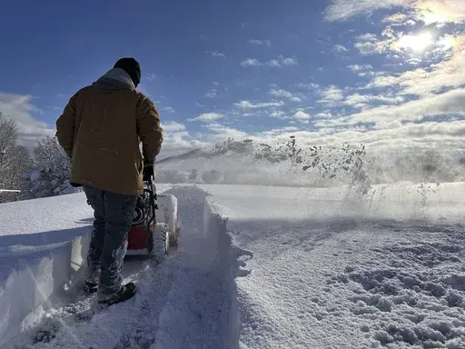 A man plows a sidewalk after a snow storm in Lowville, N.Y., Monday, Dec. 2, 2024. (AP Photo/Cara Anna)