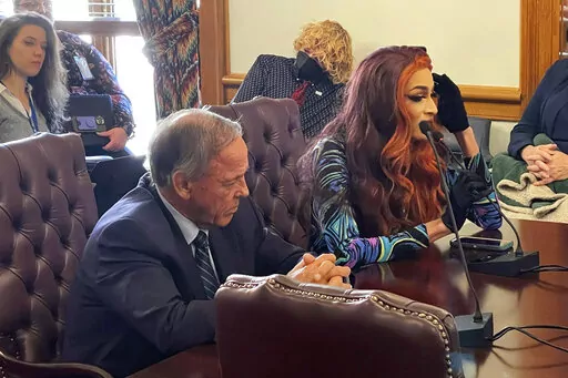 Drag performer MD Hunter, whose stage name is Athena Sinclair, testifies before a state Senate panel as state Sen. Gary Stubblefield, left, listens, at the Arkansas Capitol in Little Rock, Ark., on Thursday, Jan. 19, 2023. The Senate panel endorsed a bill by Stubblefield that would restrict where drag performances can be shown by classifying them as adult oriented businesses. (AP Photo/Andrew DeMillo)