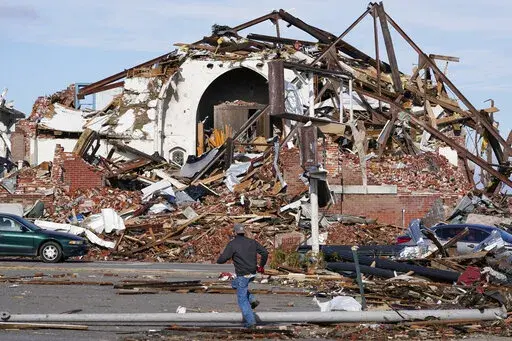 People survey damage from a tornado is seen in Mayfield, Ky., on Saturday, Dec. 11, 2021. Tornadoes and severe weather caused catastrophic damage across multiple states late Friday, killing several people overnight. (AP Photo/Mark Humphrey)
