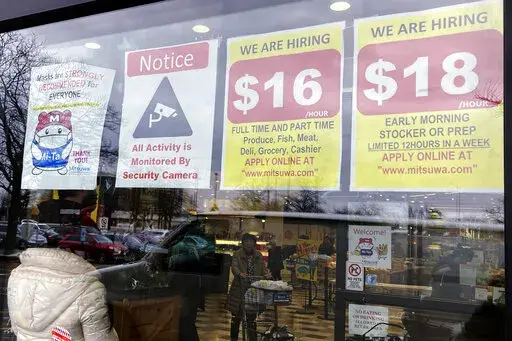 Hiring signs are displayed at a grocery store in Arlington Heights, Ill., Friday, Jan. 13, 2023. On Tuesday, the Labor Department reports on wages and benefits for U.S. workers during the October-December quarter. (AP Photo/Nam Y. Huh, File)