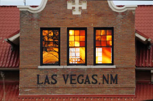 Reddened by wildfire smoke, the sun is seen reflected off windows at the train station in Las Vegas, N.M., on Saturday, May 7, 2022. Area residents have been on and off of evacuation orders of the past month as fires grow and move with intense and unpredictable winds. (AP Photo/Cedar Attanasio)