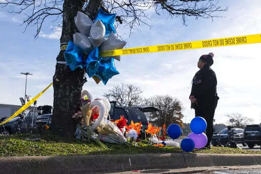Mary Chatkovsky places balloons and flowers on a memorial outside of the Chesapeake, Va., Walmart on Thursday, Nov. 24, 2022.  Andre Bing, a Walmart manager, opened fire on fellow employees in the break room of the Virginia store, killing six people in the country’s second high-profile mass shooting in four days, police and witnesses said Wednesday. (Billy Schuerman/The Virginian-Pilot via AP)
