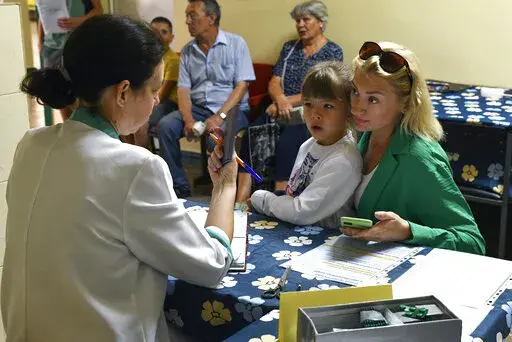 People receive iodine-containing tablets at a distribution point in Zaporizhzhia, Ukraine, Friday, Aug. 26, 2022. A mission from the U.N.'s International Atomic Energy Agency is expected to visit the Zaporizhzhia nuclear power plant next week after it was temporarily knocked offline and more shelling was reported in the area overnight, Ukrainian officials said Friday. (AP Photo/Andriy Andriyenko)