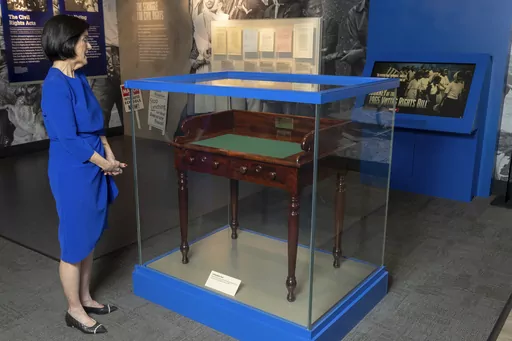 Luci Baines Johnson looks at the desk on May 16, 2023, on display at the LBJ Presidential Library, that President Lyndon B. Johnson sat at in the President's Room at the U.S. Capitol to sign the Voting Rights Act of 1965, on Aug. 6, 1965. Concern for U.S. democracy amid deep national polarization has prompted the entities supporting 13 presidential libraries dating back to Herbert Hoover to call for a recommitment to the country's bedrock principles, including the rule of law and respecting a di