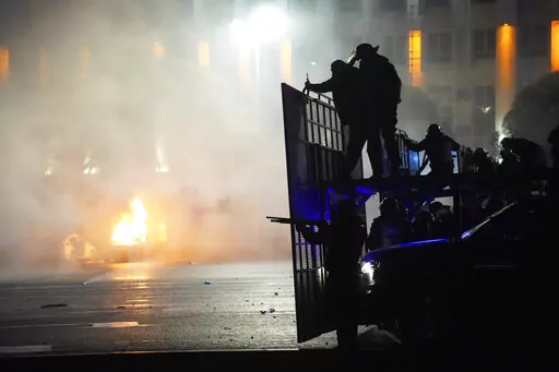 A police car on fire as riot police prepare to stop protesters in the center of Almaty, Kazakhstan, on Jan. 5, 2022. China gave strong verbal backing to Kazakhstan’s leader for his deadly crackdown to quell violent unrest, but stood aside as Russia sent in special forces troops.  (AP Photo/Vladimir Tretyakov, File)