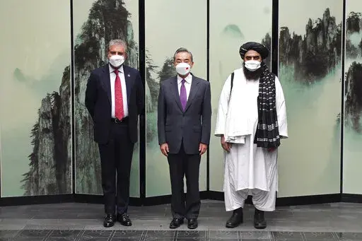 In this photo released by Xinhua News Agency, Chinese Foreign Minister Wang Yi pose for photos next to Pakistan Foreign Minister Shah Mahmood Qureshi at left and Taliban-appointed Afghanistan Foreign Minister Amir Khan Muttaqi at right during a meeting held in Tunxi district in eastern China's Anhui province on Wednesday, March 30, 2022. Chinese leader Xi Jinping on Thursday issued strong backing for Afghanistan at a regional conference, while making no mention of human rights abuses by the coun