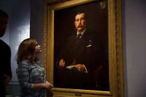 A Museum of London employee poses for photographers next to an 1897 oil on canvas portrait of Sherlock Holmes author Sir Arthur Conan Doyle by illustrator Sidney Paget on display as part of the exhibition "Sherlock Holmes: The Man Who Never Lived and Will Never Die" at the Museum of London in London, Oct. 16, 2014. Sherlock Holmes is finally free to the public in 2023. The long dispute on contested copyright on Doyle's tales of a whip-smart detective will come to an end in 2022, as the final She