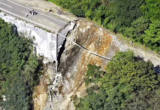 A collapsed road is seen following a typhoon in Morotsuka, Miyazaki prefecture, Tuesday, Sept. 20, 2022. A tropical storm that dumped heavy rain as it cut across Japan moved into the Pacific Ocean on Tuesday after killing a few and injuring more than 100, paralyzing traffic and leaving thousands of homes without power.(Kyodo News via AP)